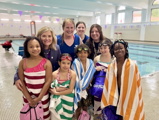 adults and students at the pool with beach towels wrapped around them